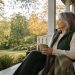 Woman relaxing with a warm drink on a porch during a peaceful fall afternoon.